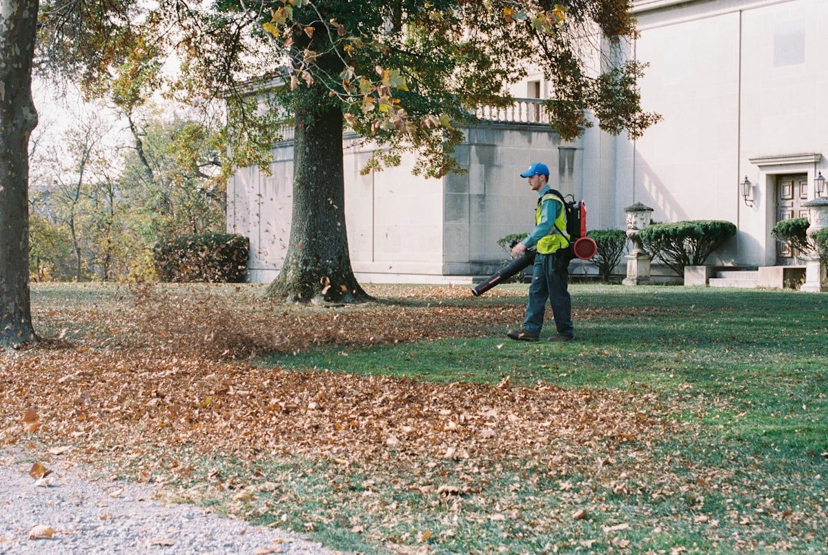 Crew member clearing fallen leaves with a backpack blower